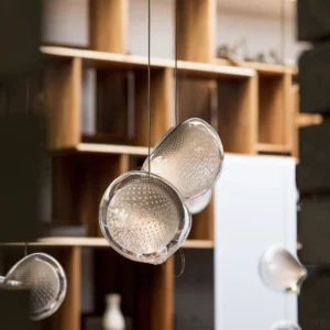Close-up detail of mesh glass pendant showing textured dimpled surface and suspended white glass tendrils within clear interstitial space