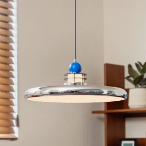 Modern saucer pendant with integrated LED glowing warmly above vintage wooden shelf in Scandinavian interior
