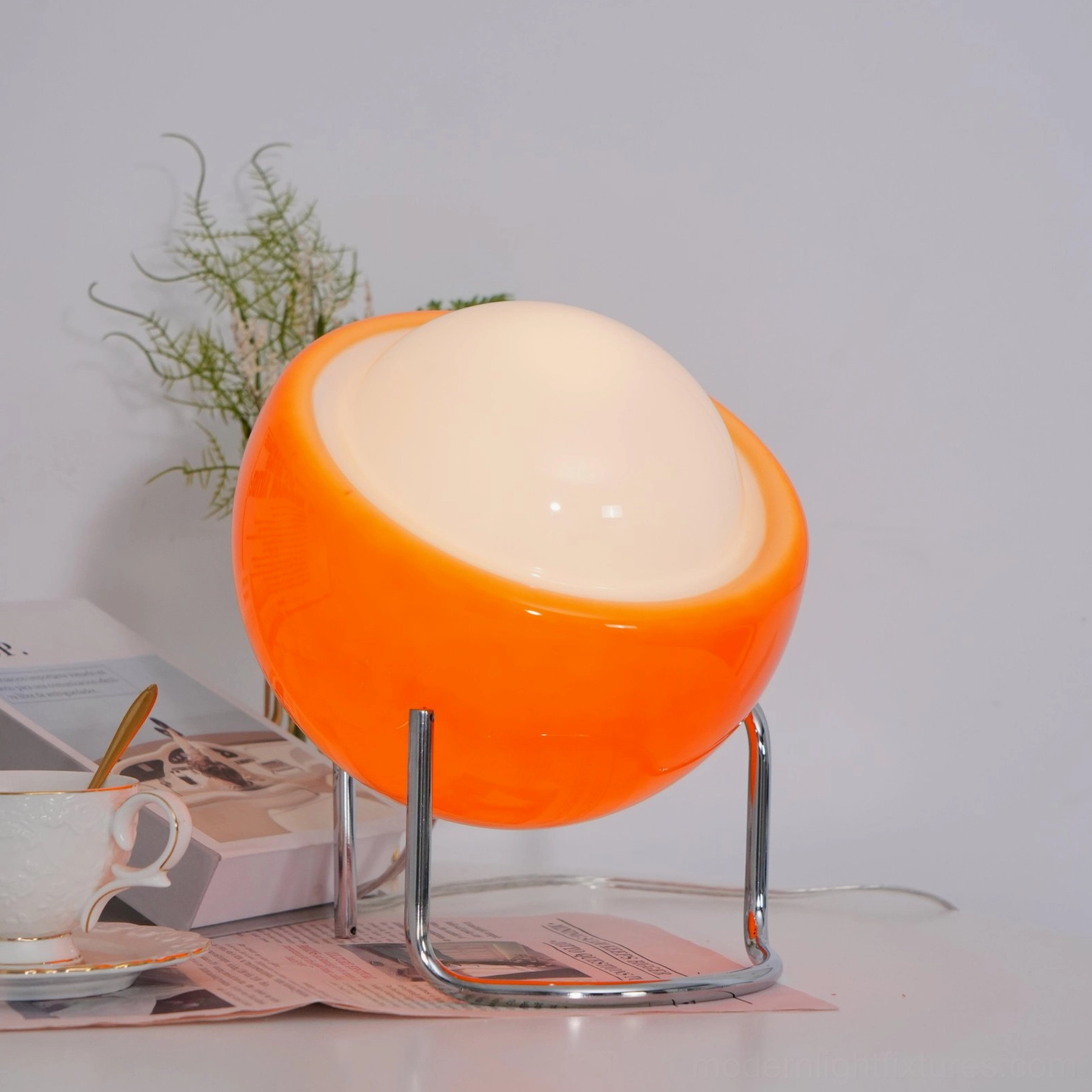 Mid-century dome table lamp with smooth glass shade and sculptural metal frame, minimalist design aesthetic