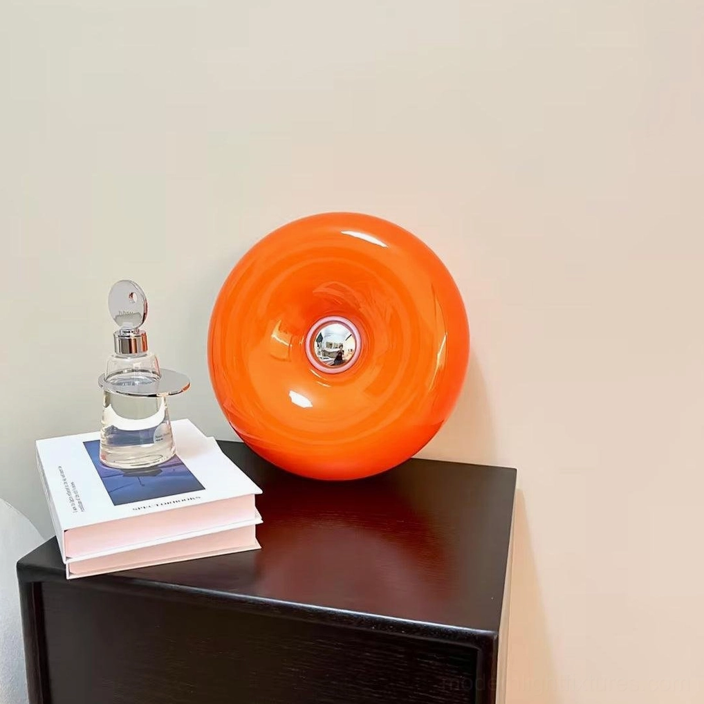 Mid-century orange donut lamp three-quarter view on side table with stacked books and home décor