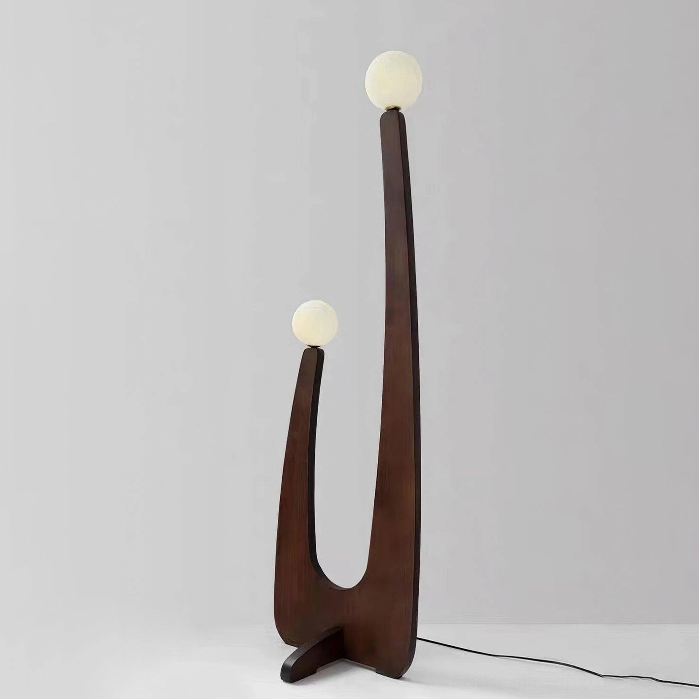 Mid-century oak floor lamp with frosted glass globes positioned in contemporary bedroom reading corner