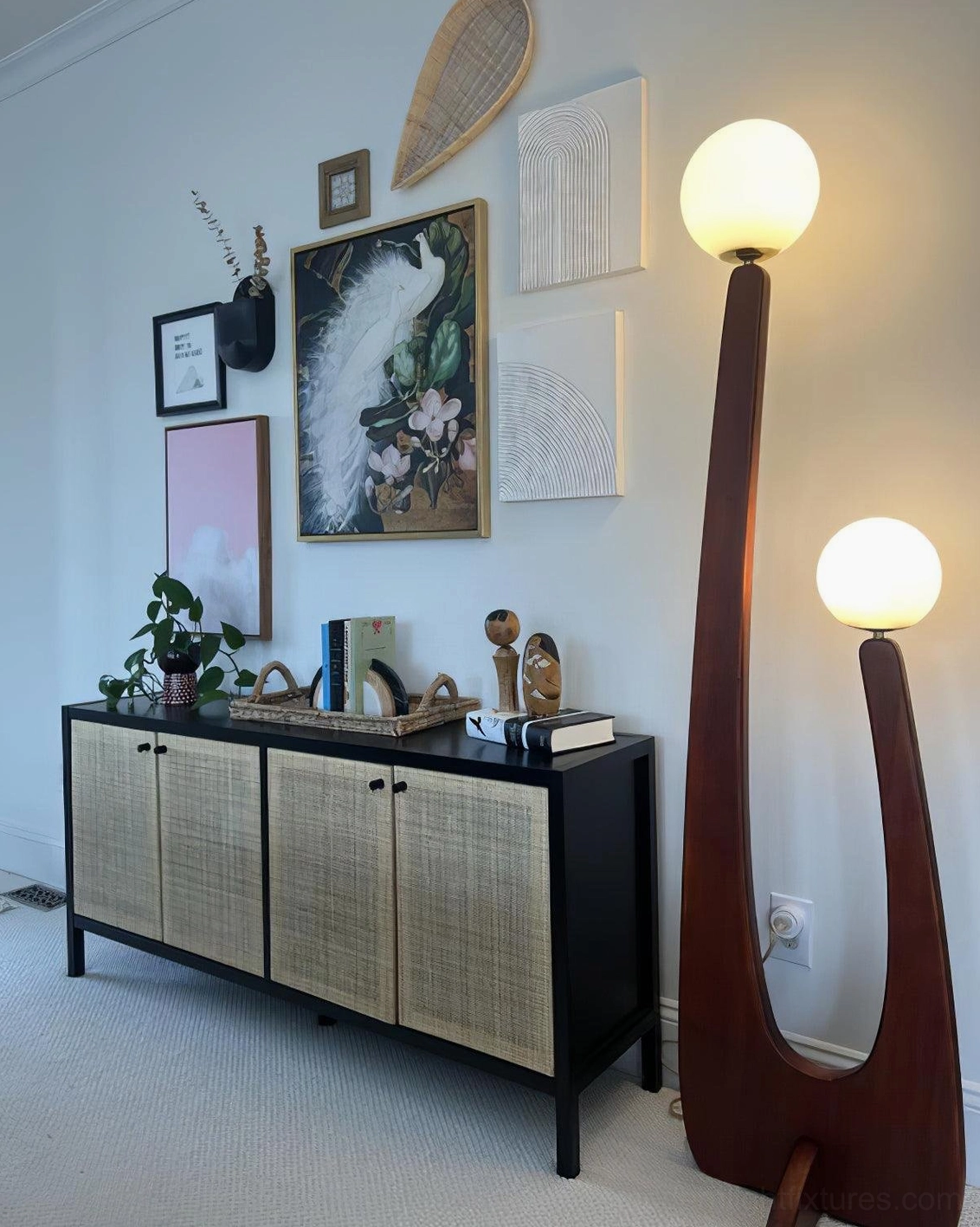 Sculptural wooden floor lamp in mid-century living room setting, beside vintage rattan cabinet and modern furniture