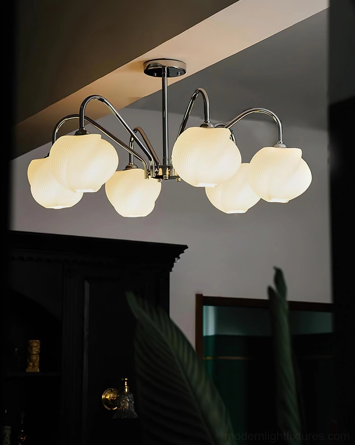 Modern sputnik chandelier with multiple arms and frosted milky glass shades suspended above tropical plant decor in luxury home bar setting