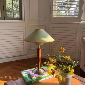 Vintage-style table lamp displayed on side table in living room setting, paired with stacked books and yellow flower arrangement