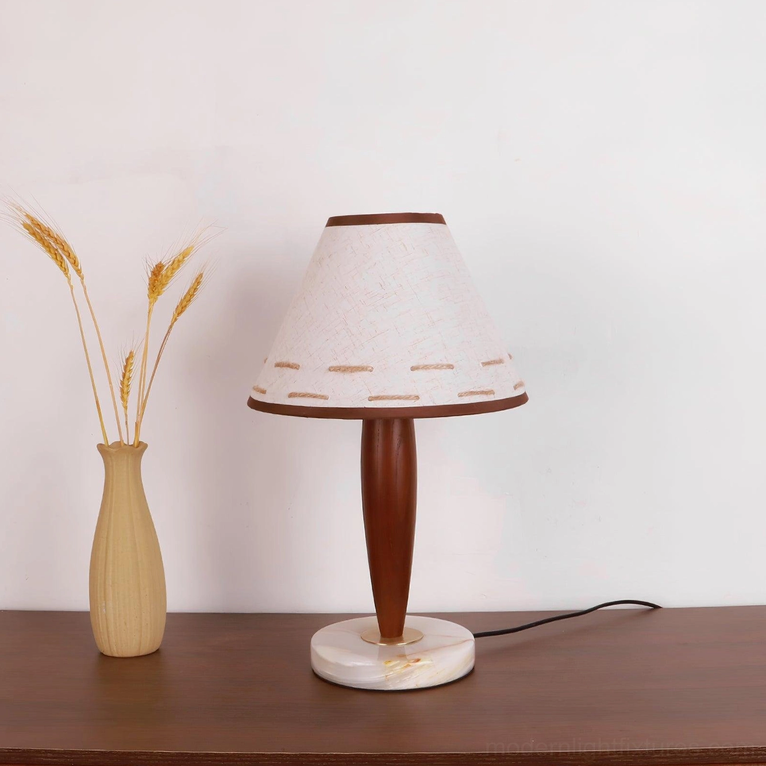 Mid-century modern terracotta lamp on wooden desk beside wheat vase - minimalist home office