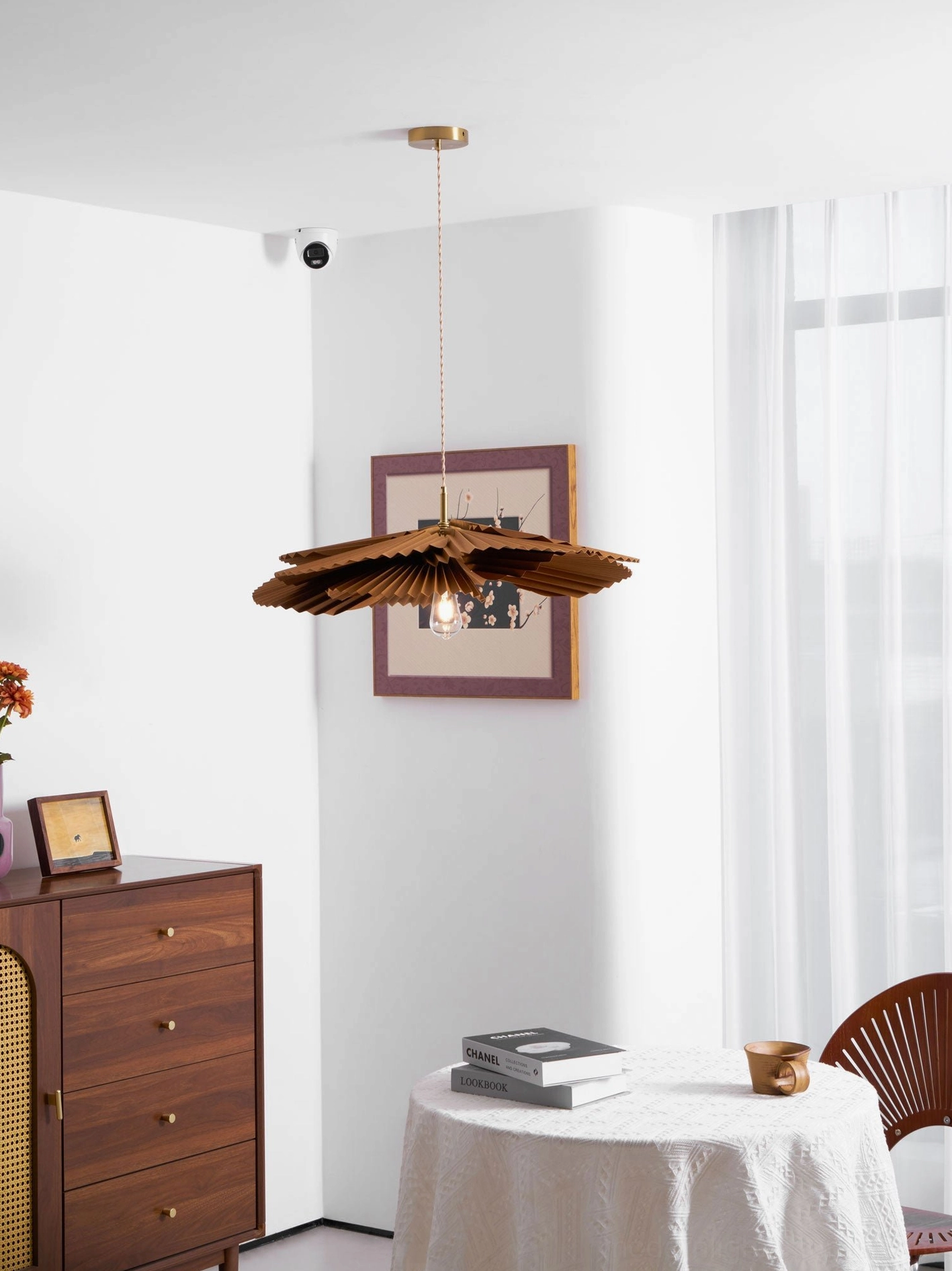 Brown kraft paper pleated pendant light illuminating dining table with warm atmospheric glow