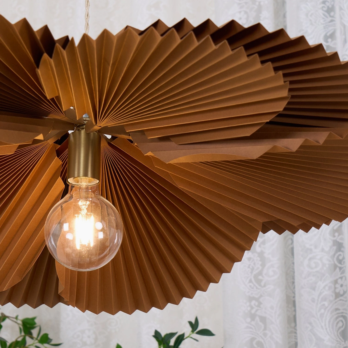 Mikado sculptural pendant fixture showing dramatic shadow patterns on ceiling and walls from pleated design