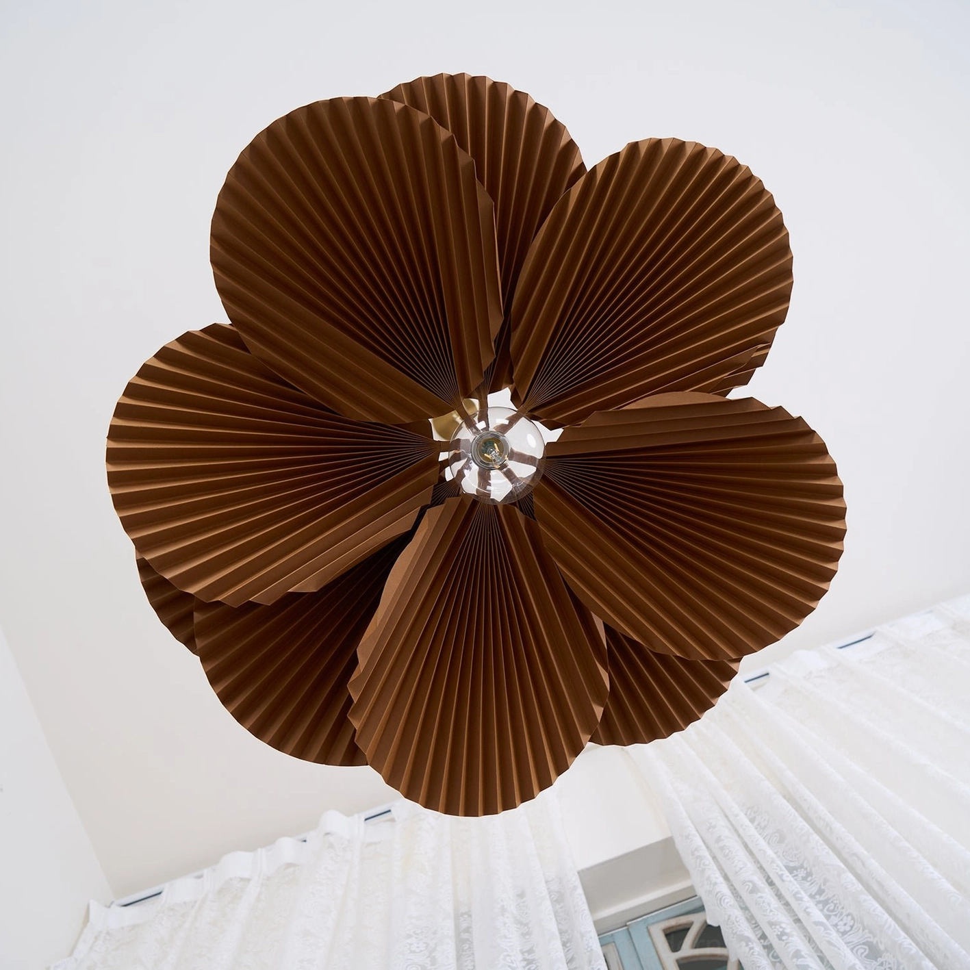 Close-up bottom view of Mikado pendant shade showing layered kraft paper pleated structure and light diffusion