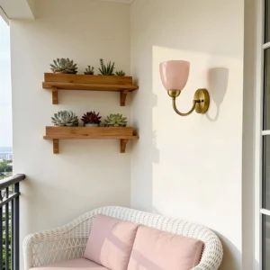 Pink glass Mild Velin wall sconce on balcony lounge corner with woven seating and shelving