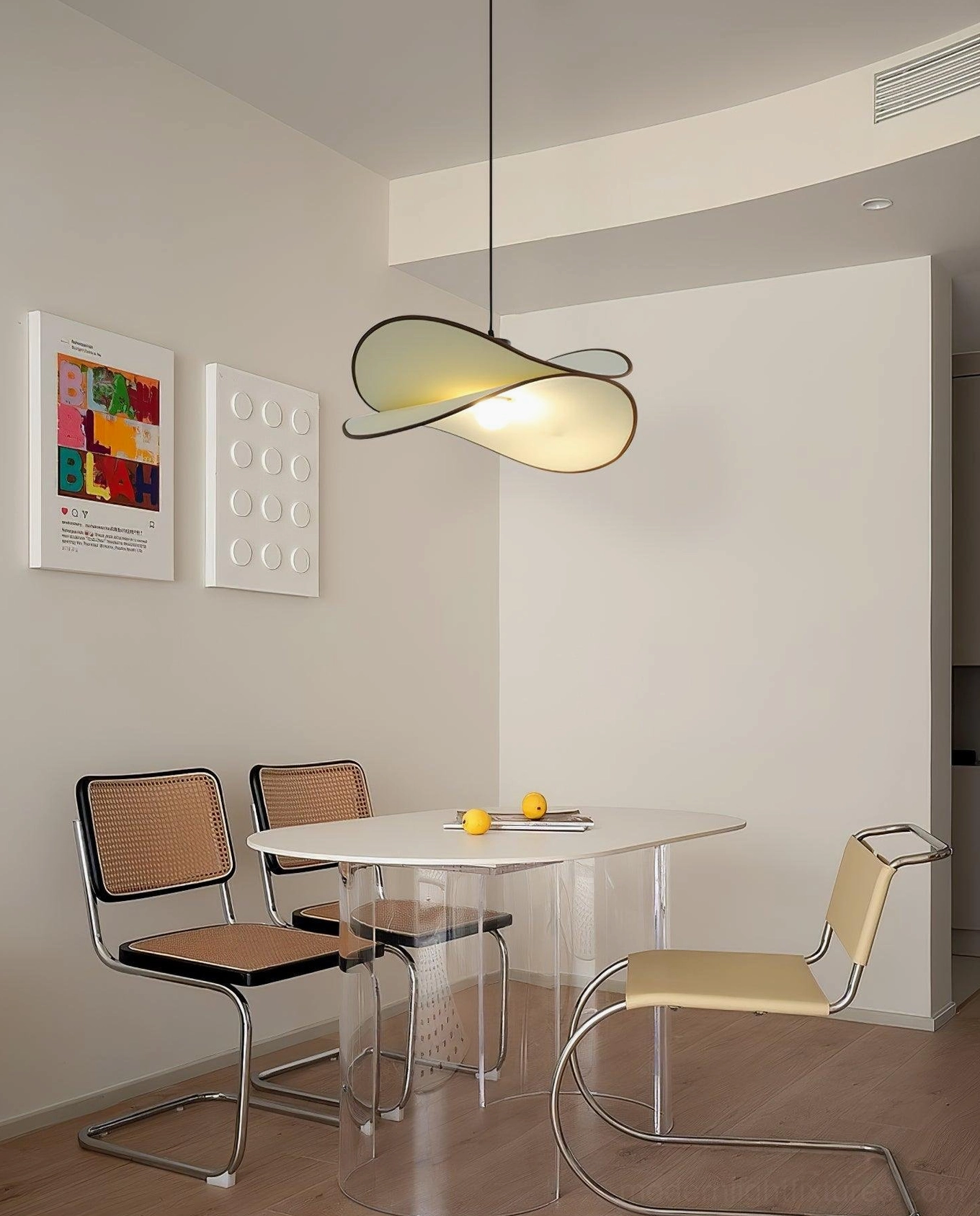 Miley twisted petal pendant lamp hanging above contemporary dining space with glass table and rattan chairs, side angle view showcasing warm neutral aesthetic