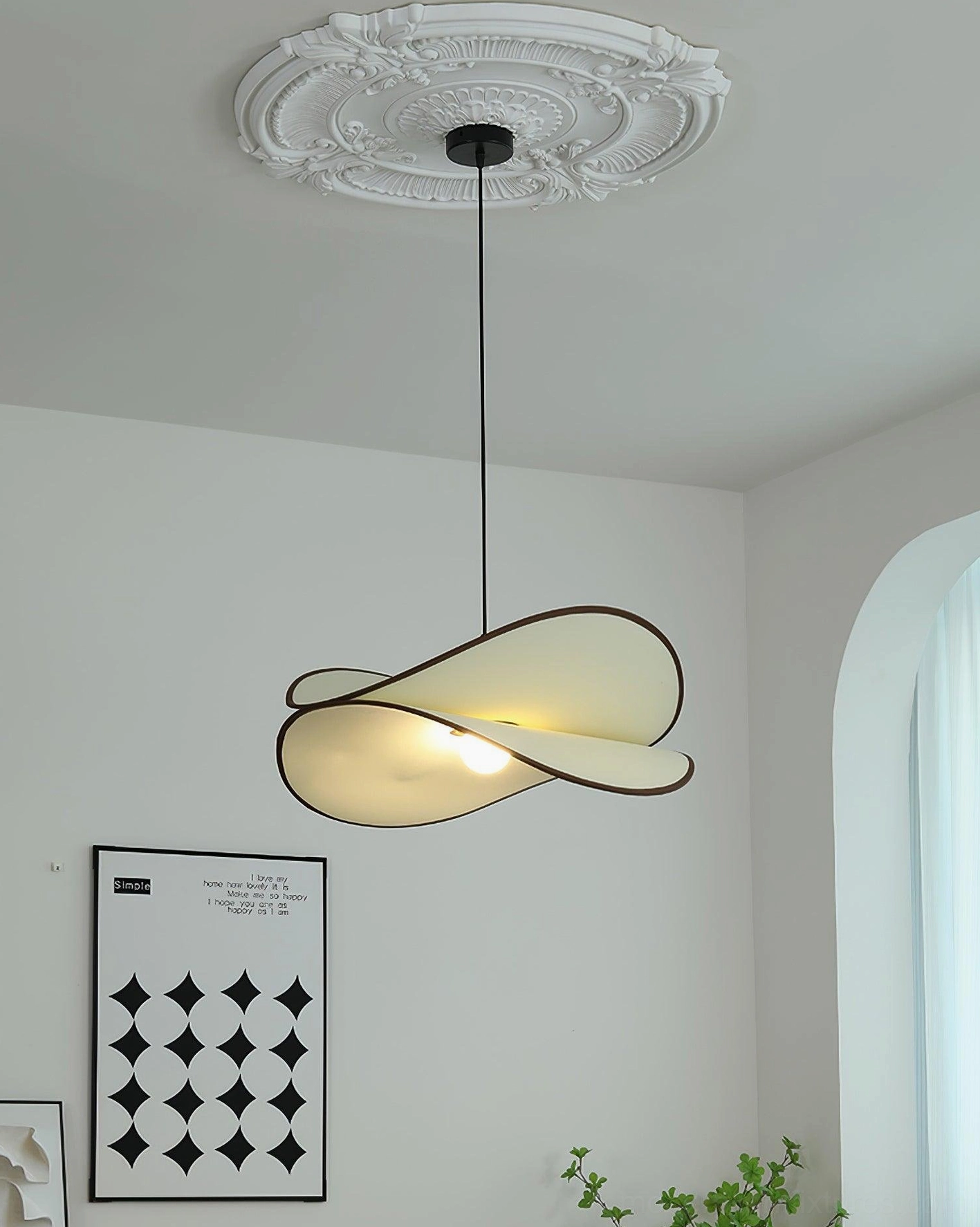 Miley modern pendant light overhead high angle view showing curved petal form suspended from ceiling, French-style room with ornate ceiling medallion and geometric wall art