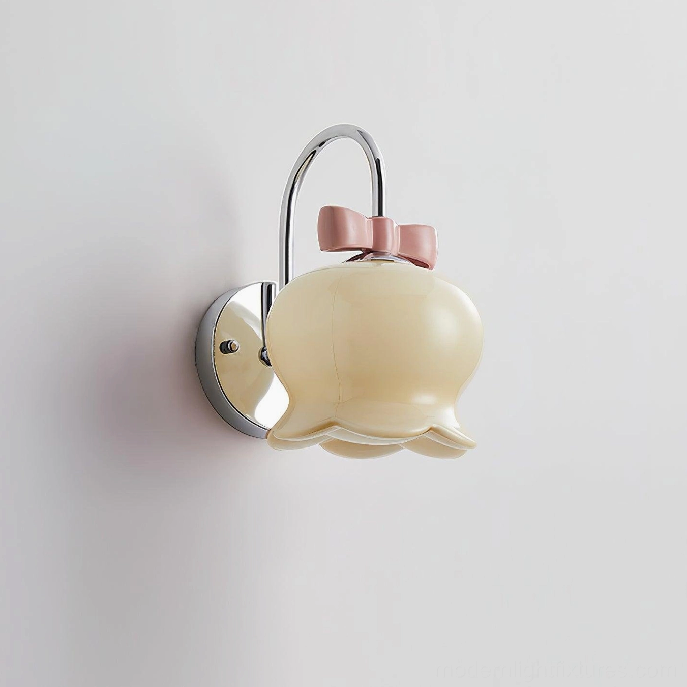 Cream yellow ceramic Millie Bells wall sconce with chrome metal hardware and pink bow detail, side wall-mounted view on minimalist background