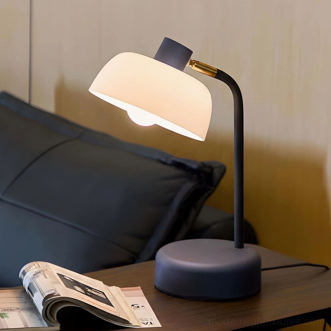 Contemporary arc table lamp with navy base and glowing frosted shade on bedroom nightstand with lit accent