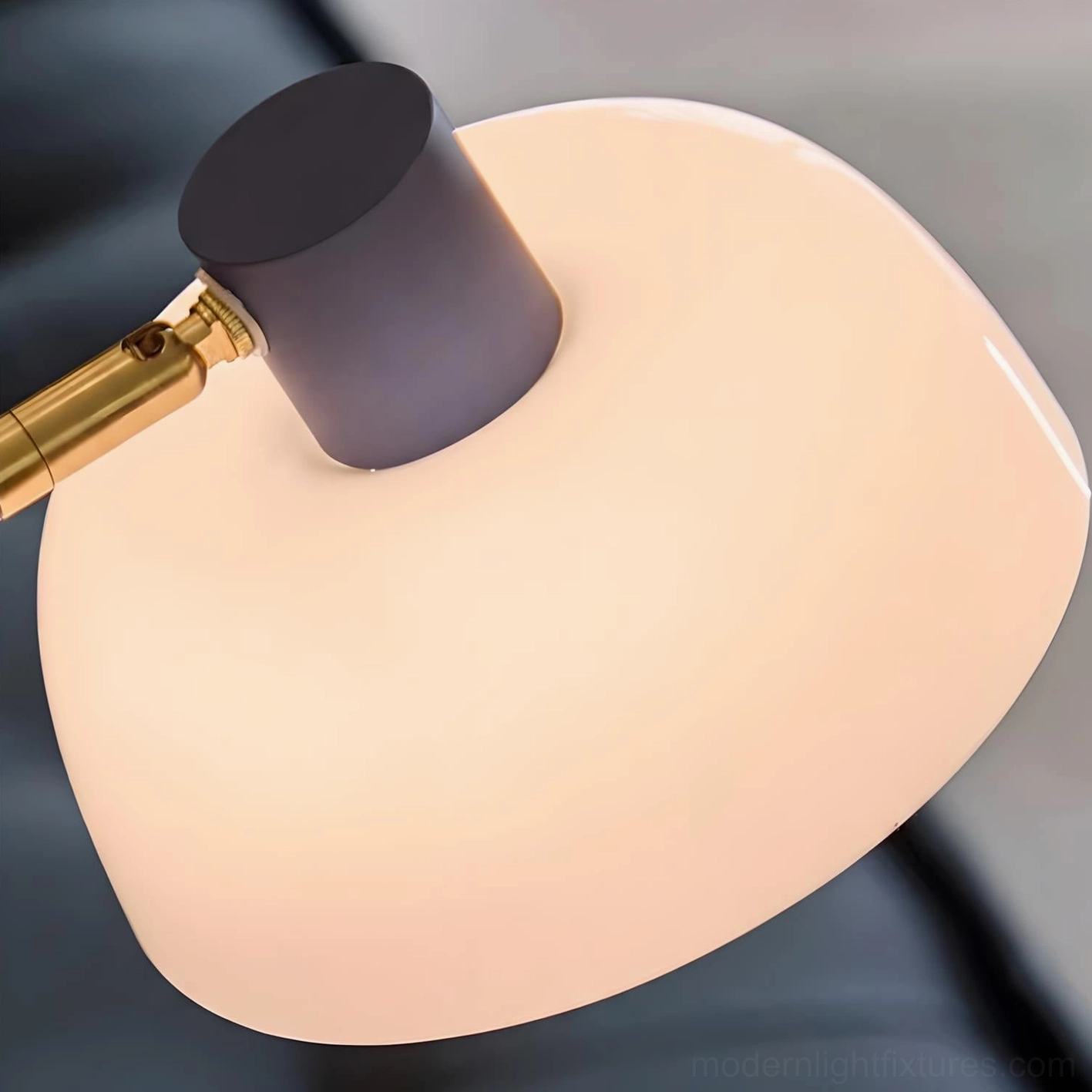 Close-up side view of arc table lamp showing gray cap, gold lamp joint, and frosted white shade detail