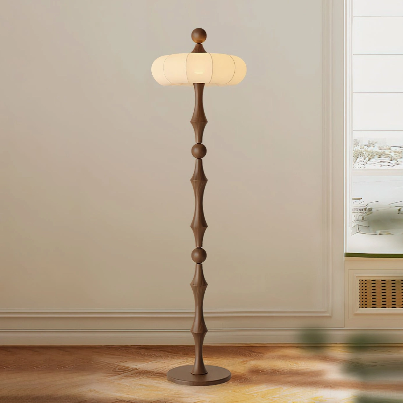 Milo wooden standing floor lamp with hand-carved walnut pole and fabric shade, three-quarter front angle in minimalist interior with wooden floor