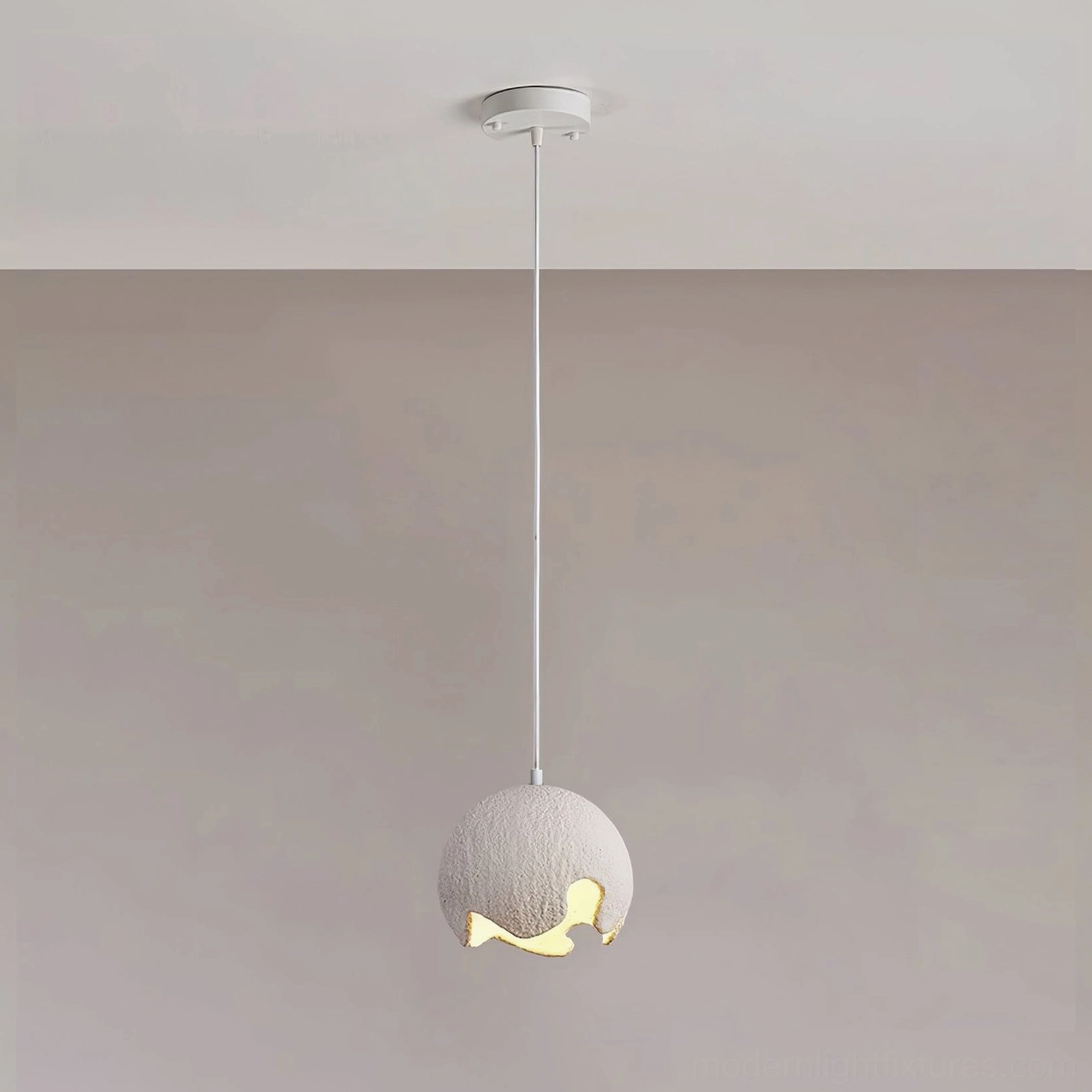 Mini white moon crater pendant lamp with small matte white spherical shade and white ceiling setup, showing warm light aperture