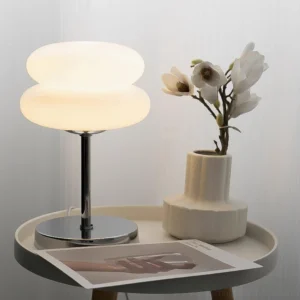 Contemporary glass table lamp displayed on home side table with decorative vases and magazines