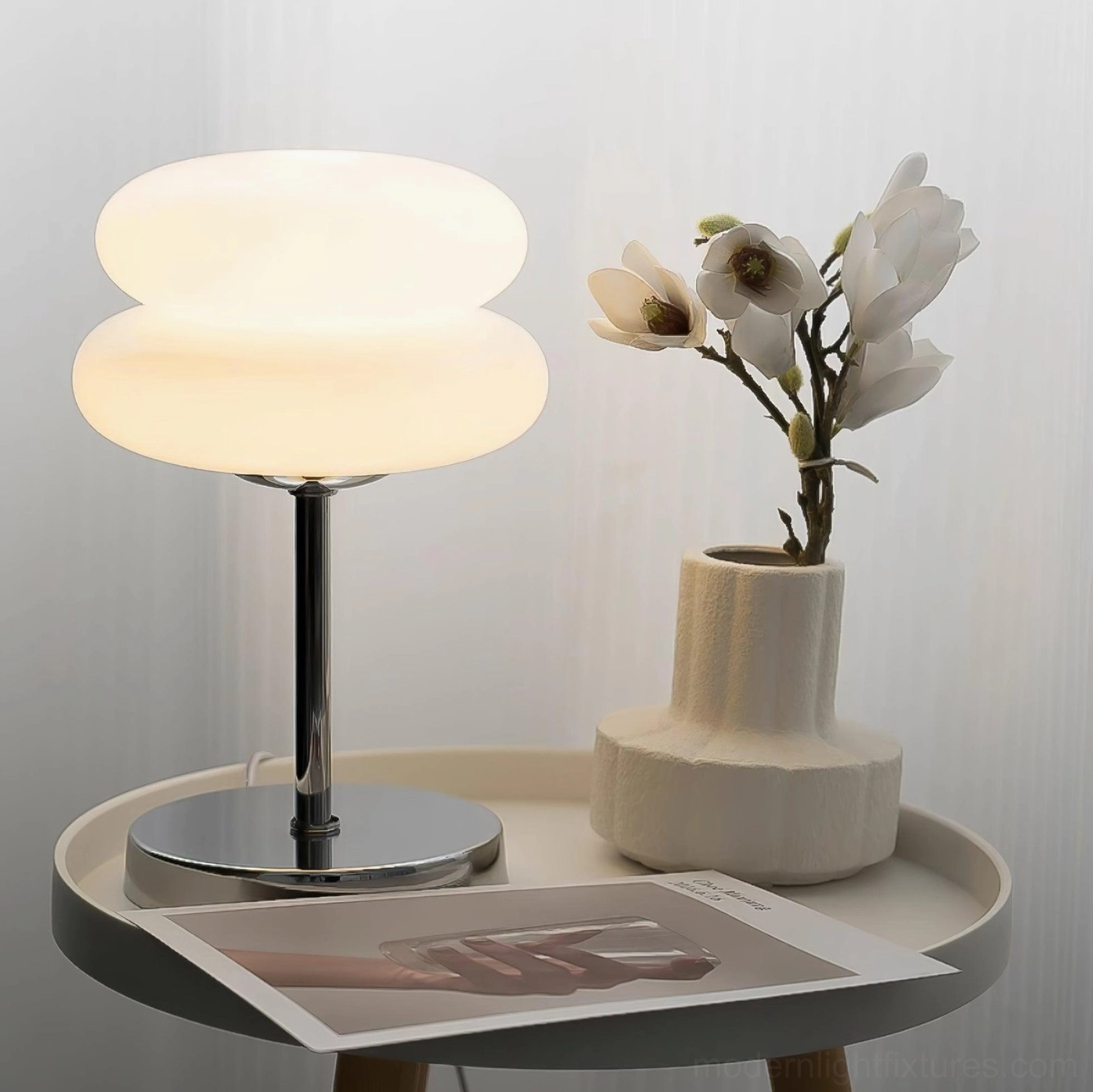 Contemporary glass table lamp displayed on home side table with decorative vases and magazines