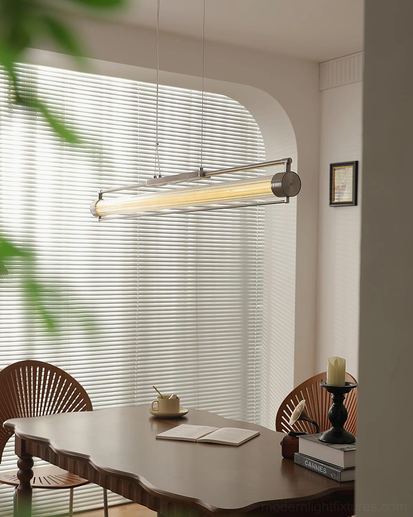 Linear glass tube pendant with warm glow in bohemian dining space - minimalist ceiling fixture with arched window