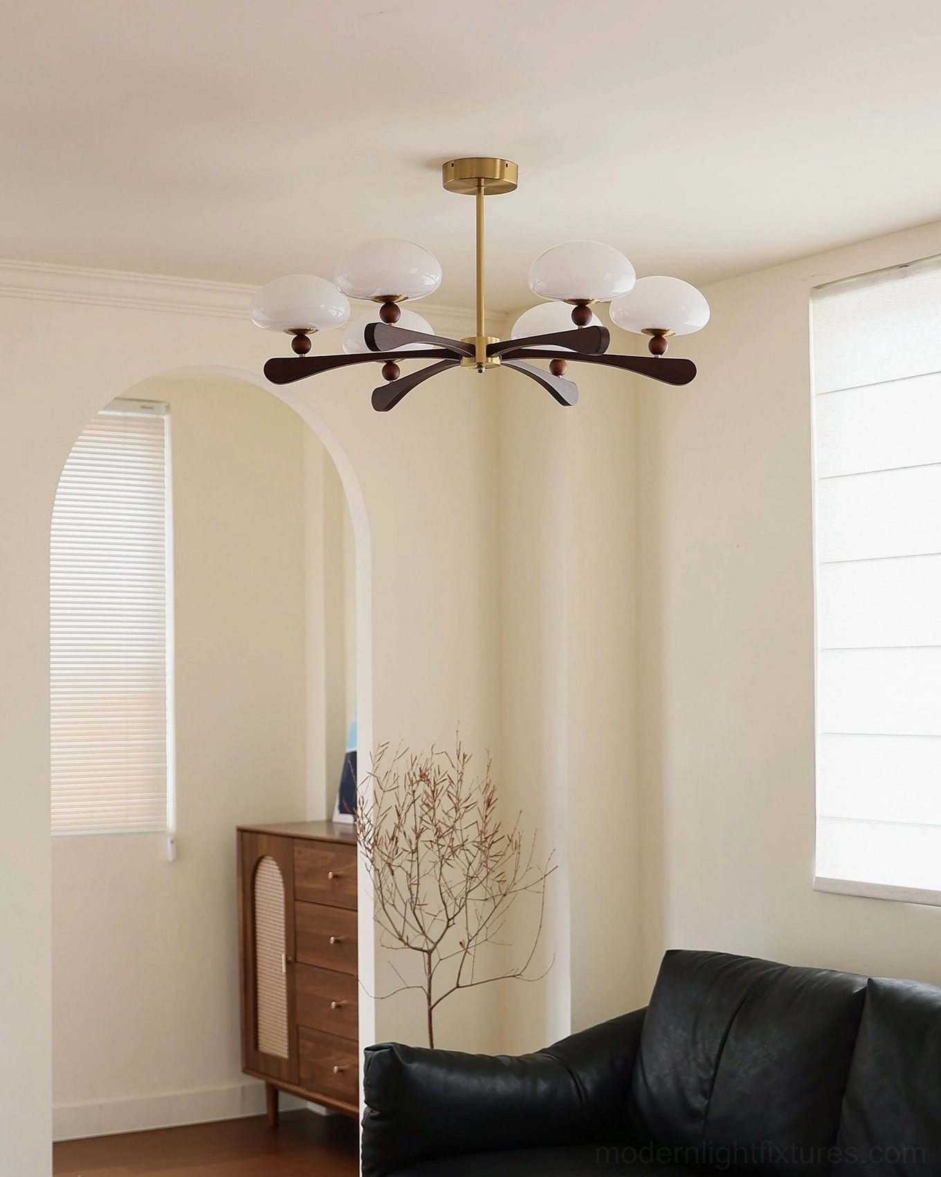 6-light modern radial pendant chandelier installed in minimalist living room with black leather sofa, dark neutral home style