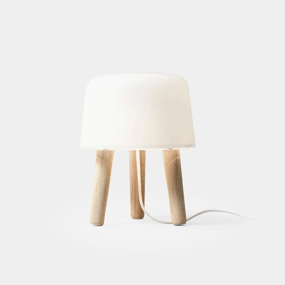 Front three-quarter view of minimalist milk glass table lamp with natural light wood tripod base on white background, showcasing Nordic minimalist design