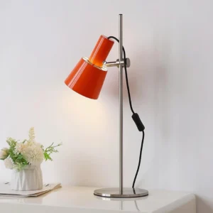 Contemporary adjustable desk lamp with orange shade displayed on home side table with minimalist decor
