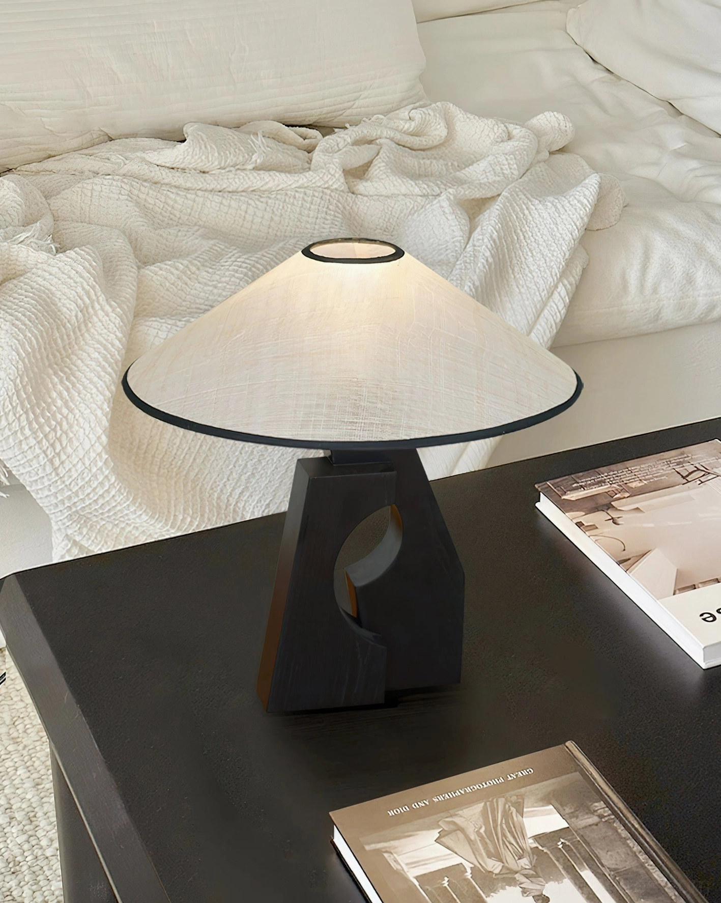 Artisanal wood table lamp with abaca shade in bedroom setting with warm cozy ambiance