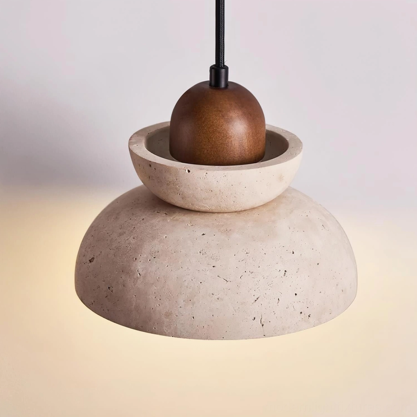 Stacked travertine pendant with glowing warm light and visible bulb from low angle view