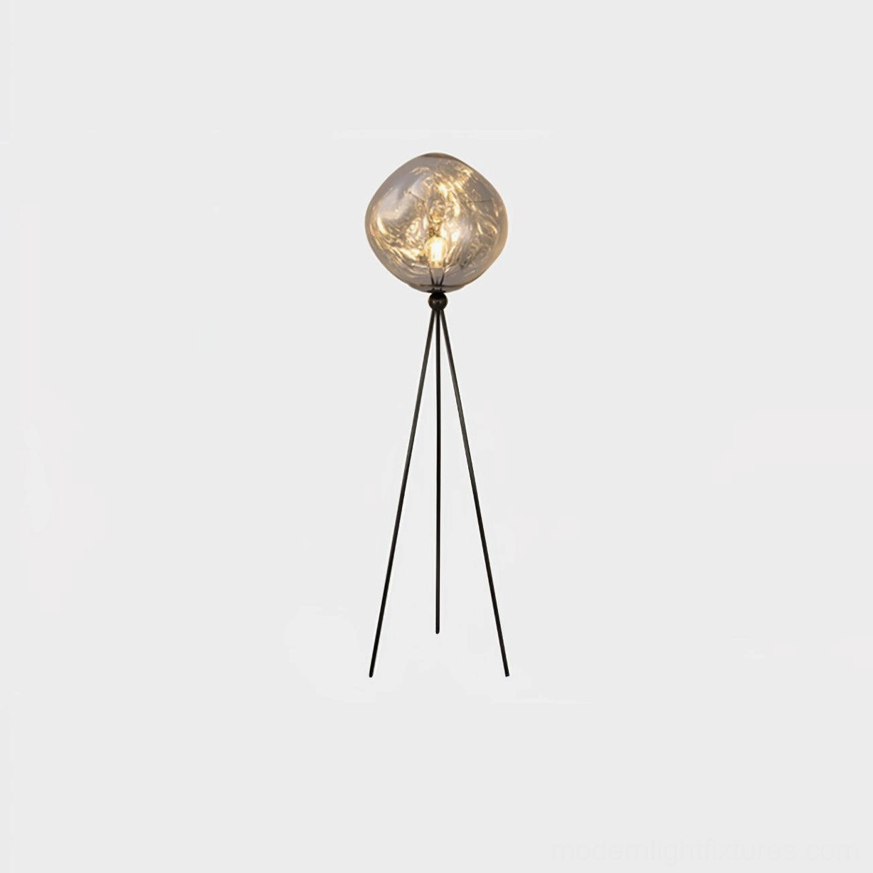 Contemporary black tripod floor lamp with round molten lava glass shade in minimalist home setting