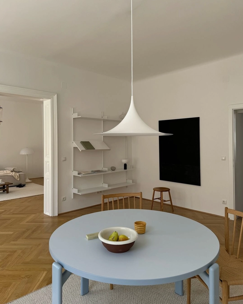Minimalist white trumpet pendant lamp in modern apartment dining area with light blue table