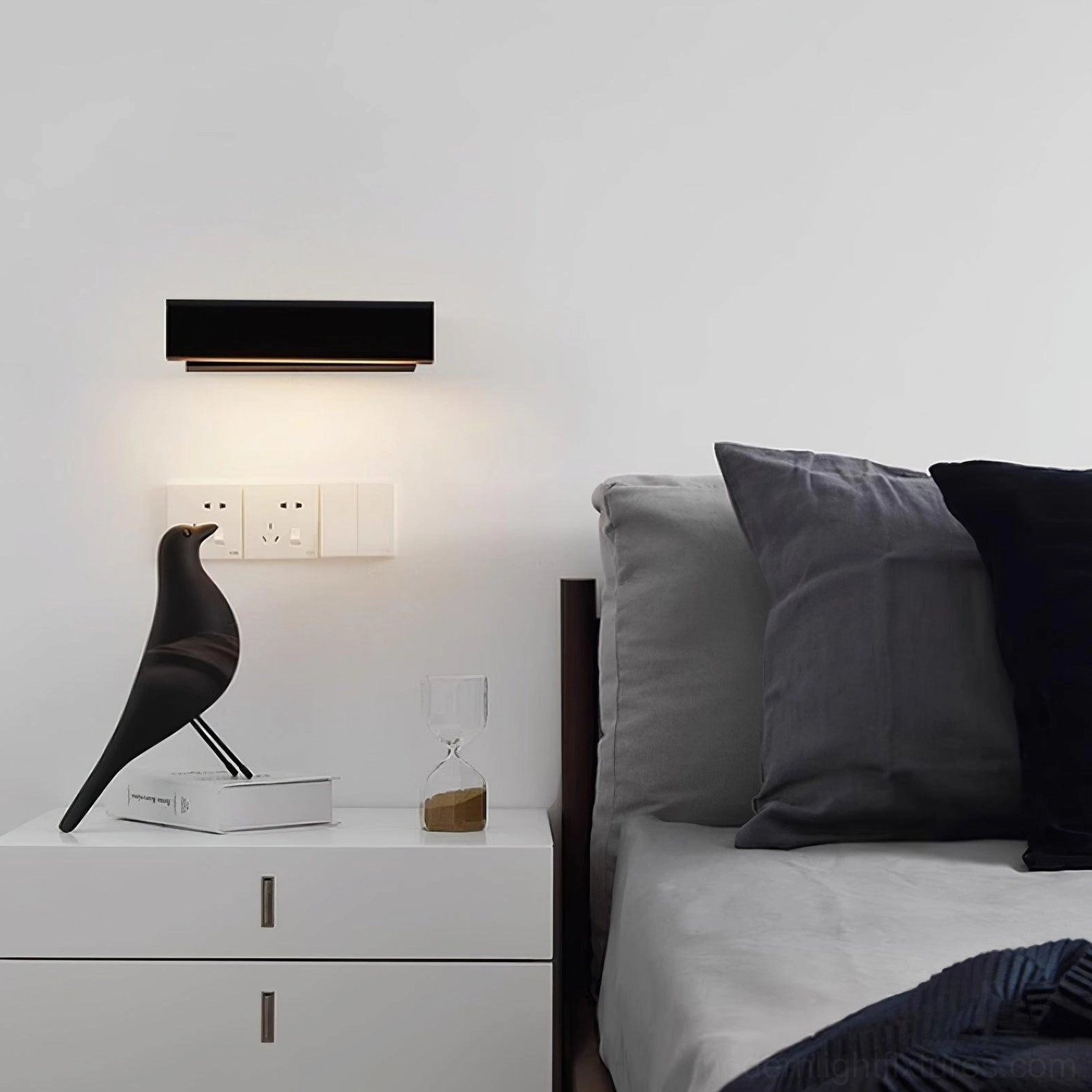 Minimalist wall lamp with matte black or white finish options, installed in modern bedroom
