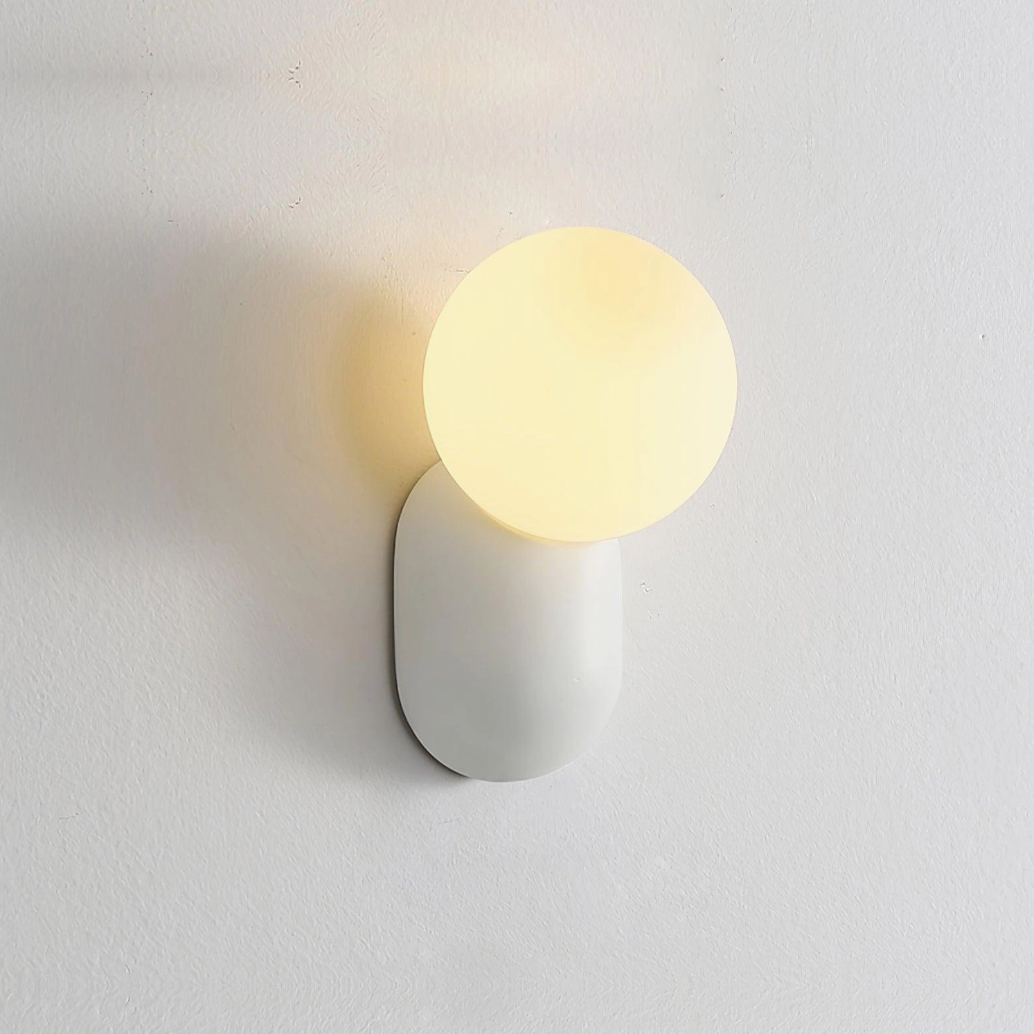 Minimalist spherical wall sconce creating focal point on neutral bedroom wall with warm illumination