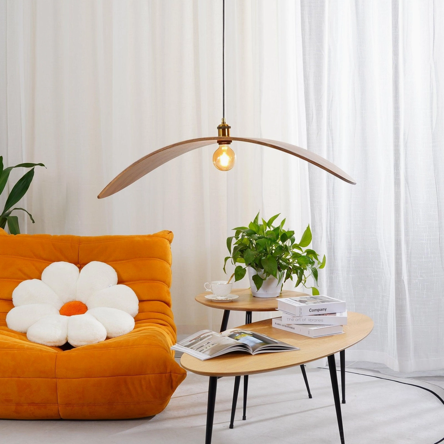 Single walnut wood leaf pendant lamp in bright minimalist living room with orange sofa, sheer curtains and green potted plants