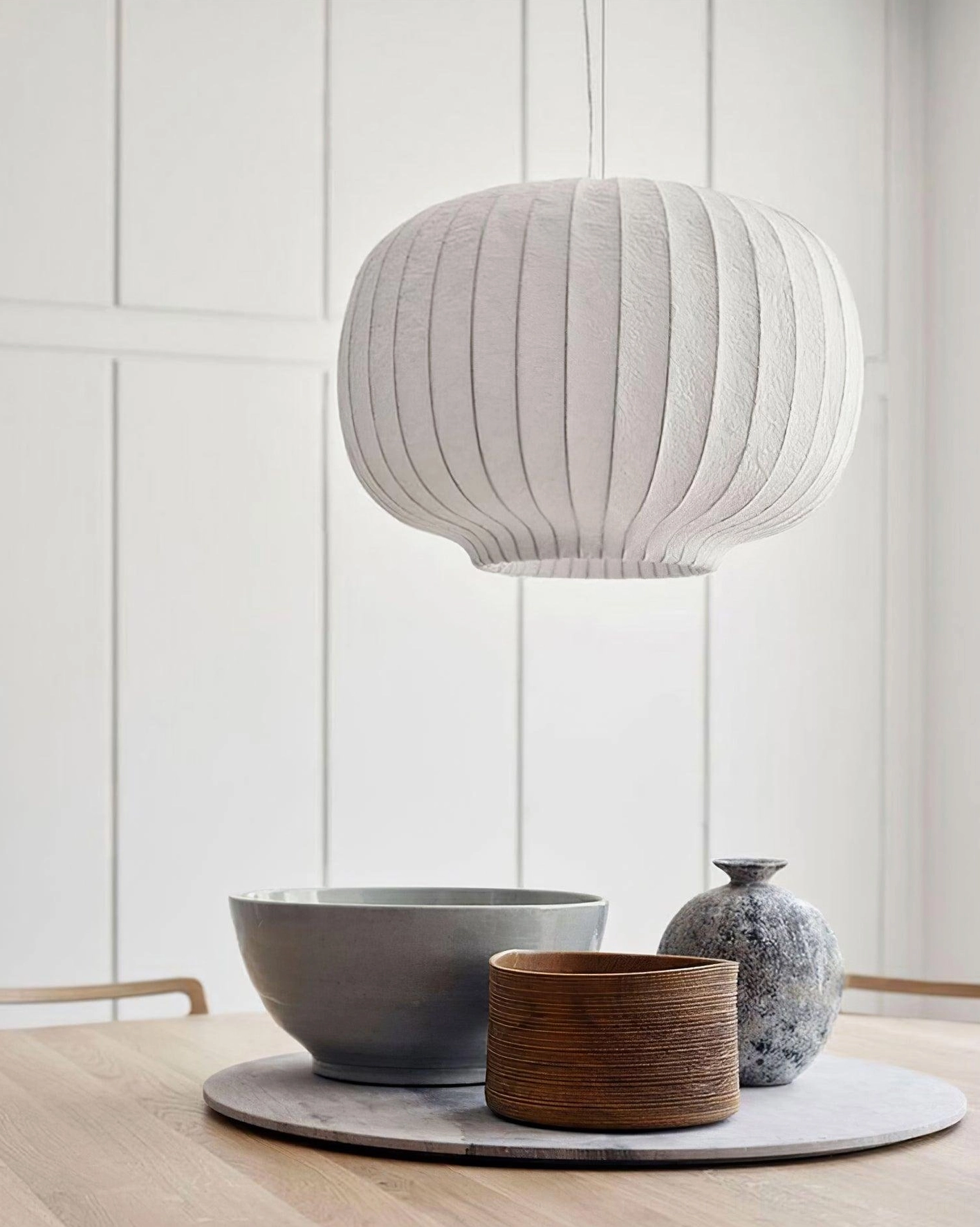 Single minimalist oval ribbed pendant light in modern home dining area with tabletop decor