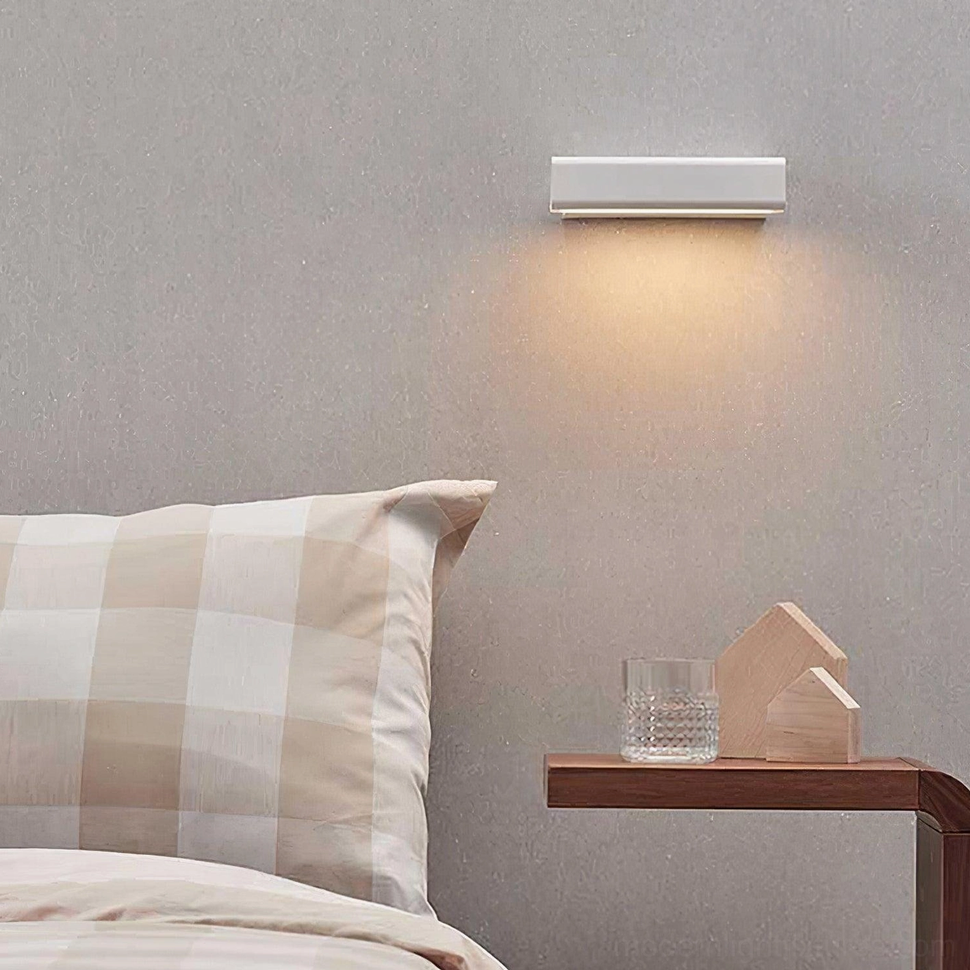 Minimalist linear wall lamp with matte white finish mounted on bedroom bedside wall, downward warm light