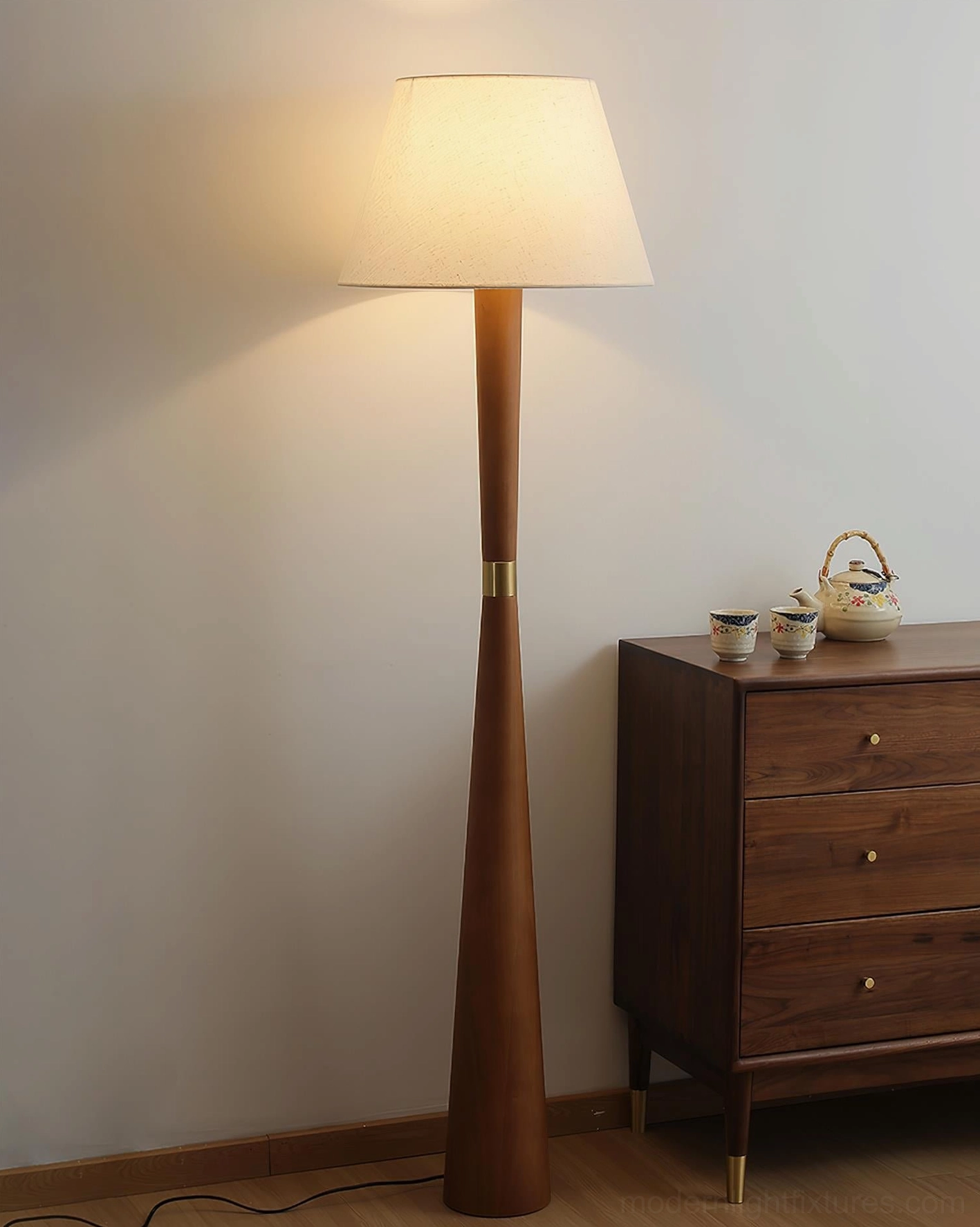 Scandinavian wooden floor lamp in walnut finish creating warm ambient light in living room corner with vintage wooden cabinet