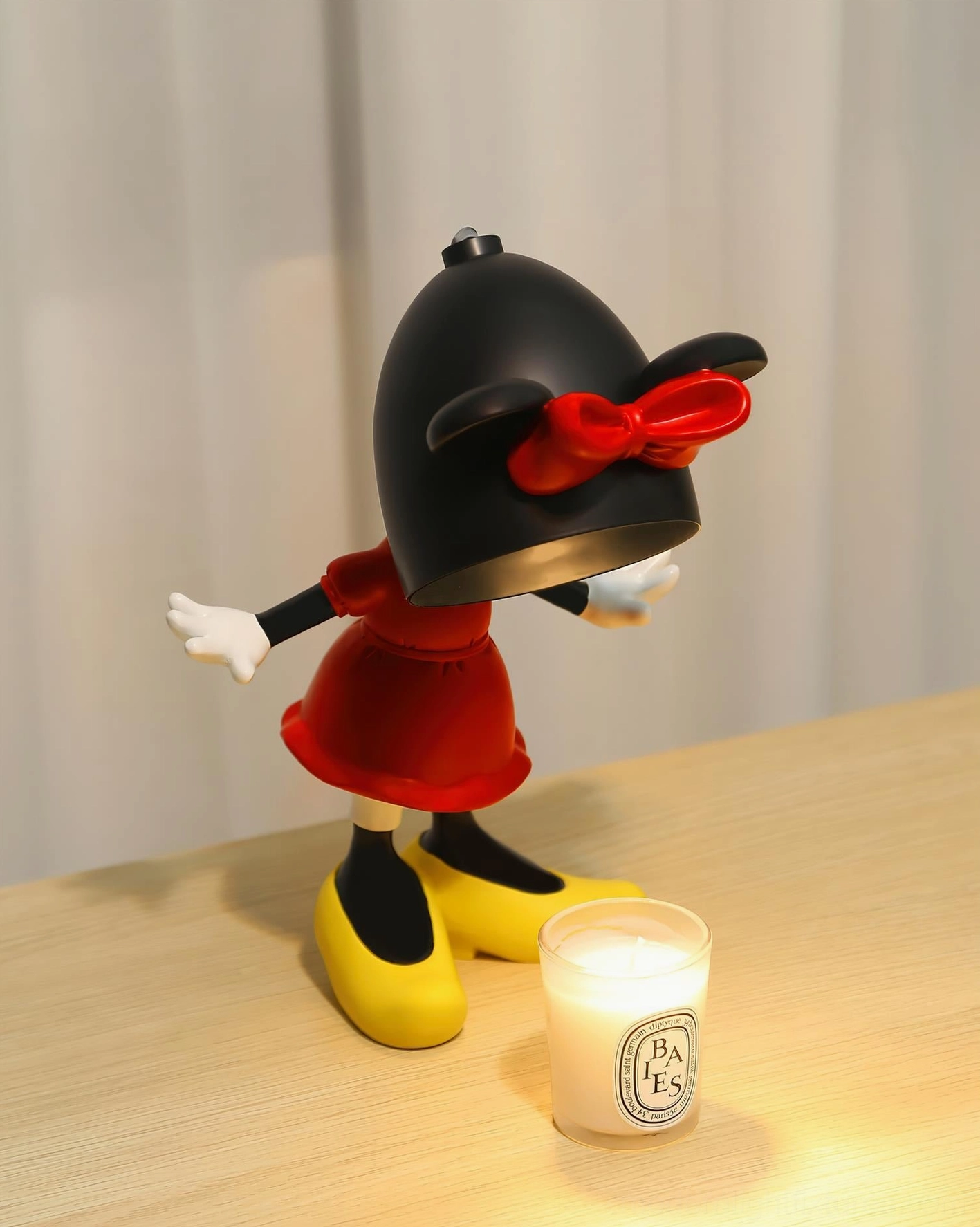 Side view of Minnie Mouse candle warmer lamp showing profile design with lit functionality and scented candle on wooden surface