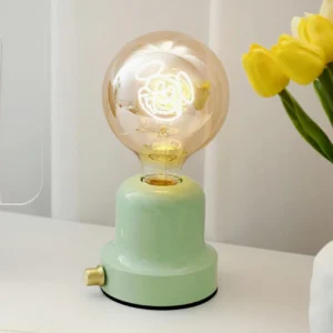 Mint green ceramic cartoon table lamp with brass side switch on tabletop with yellow tulips home décor