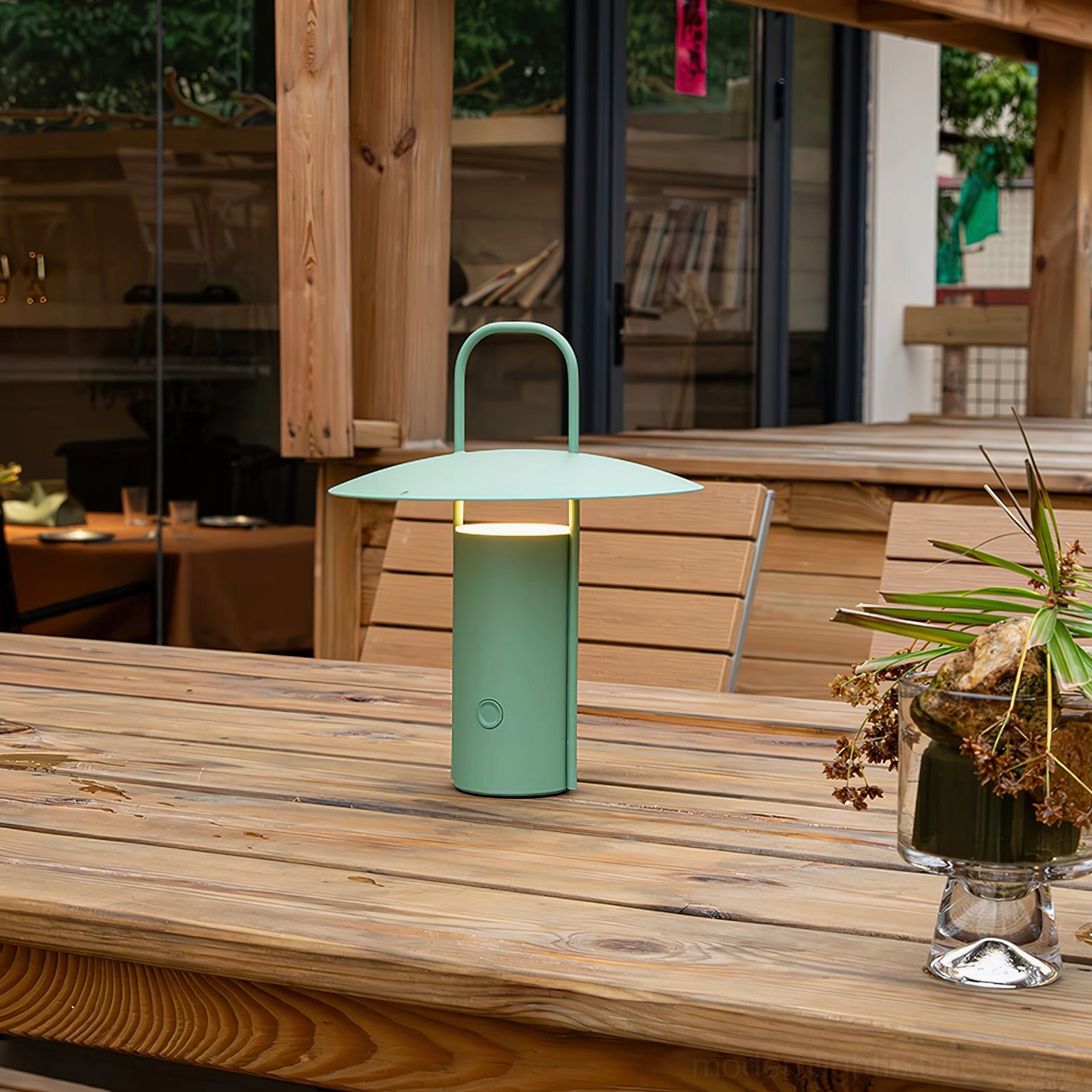 Mint green portable LED table lamp with carry handle illuminated on indoor wooden restaurant table