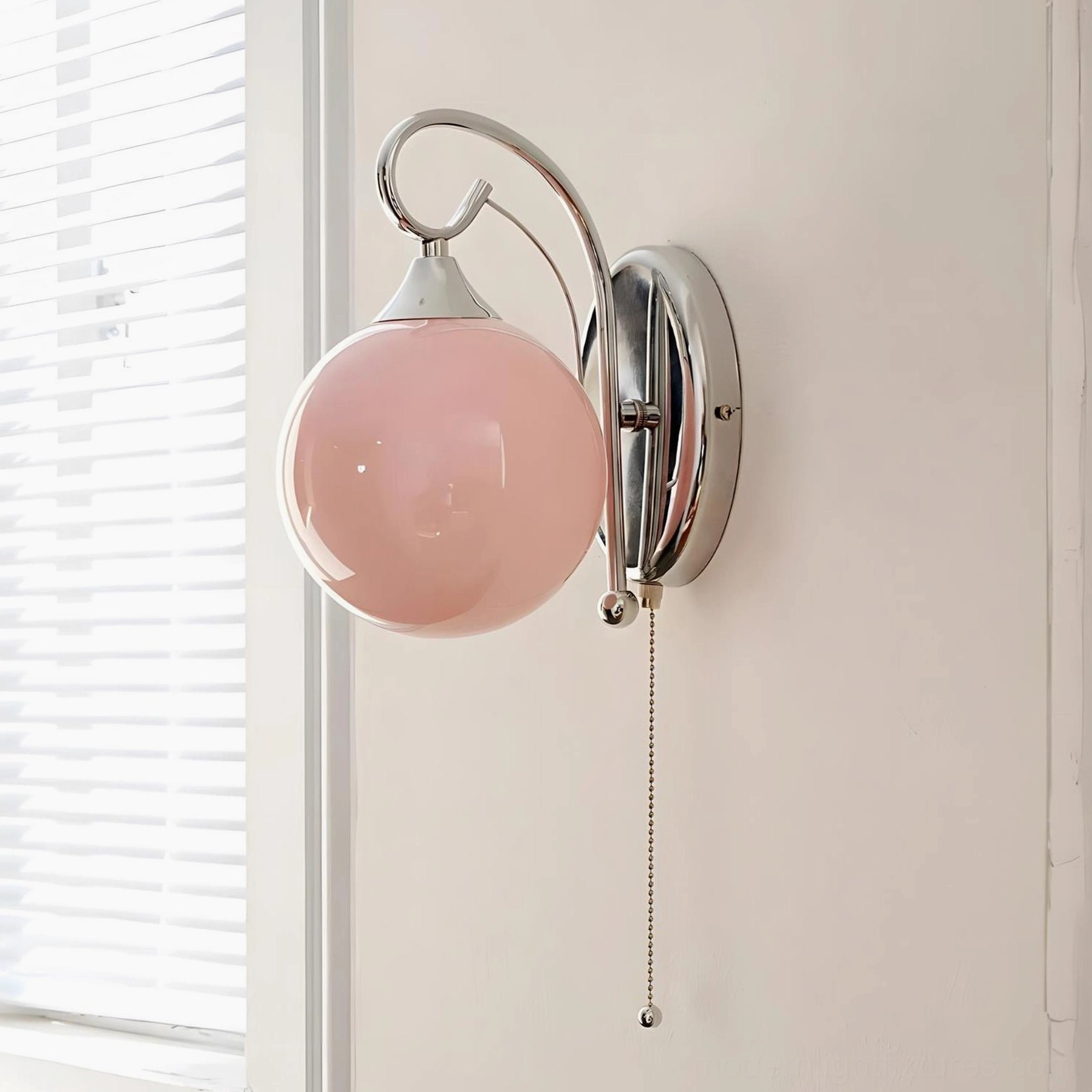 Pink glass globe wall lamp detail close-up, curved polished chrome metal frame and vintage pull-chain switch
