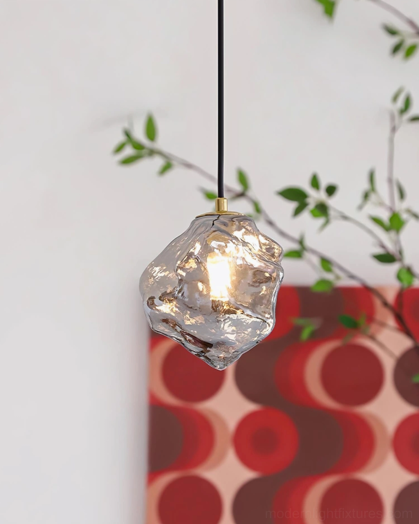 Mirza glass pendant light with lit bulb glowing amber warm light, artistic illumination in contemporary interior design