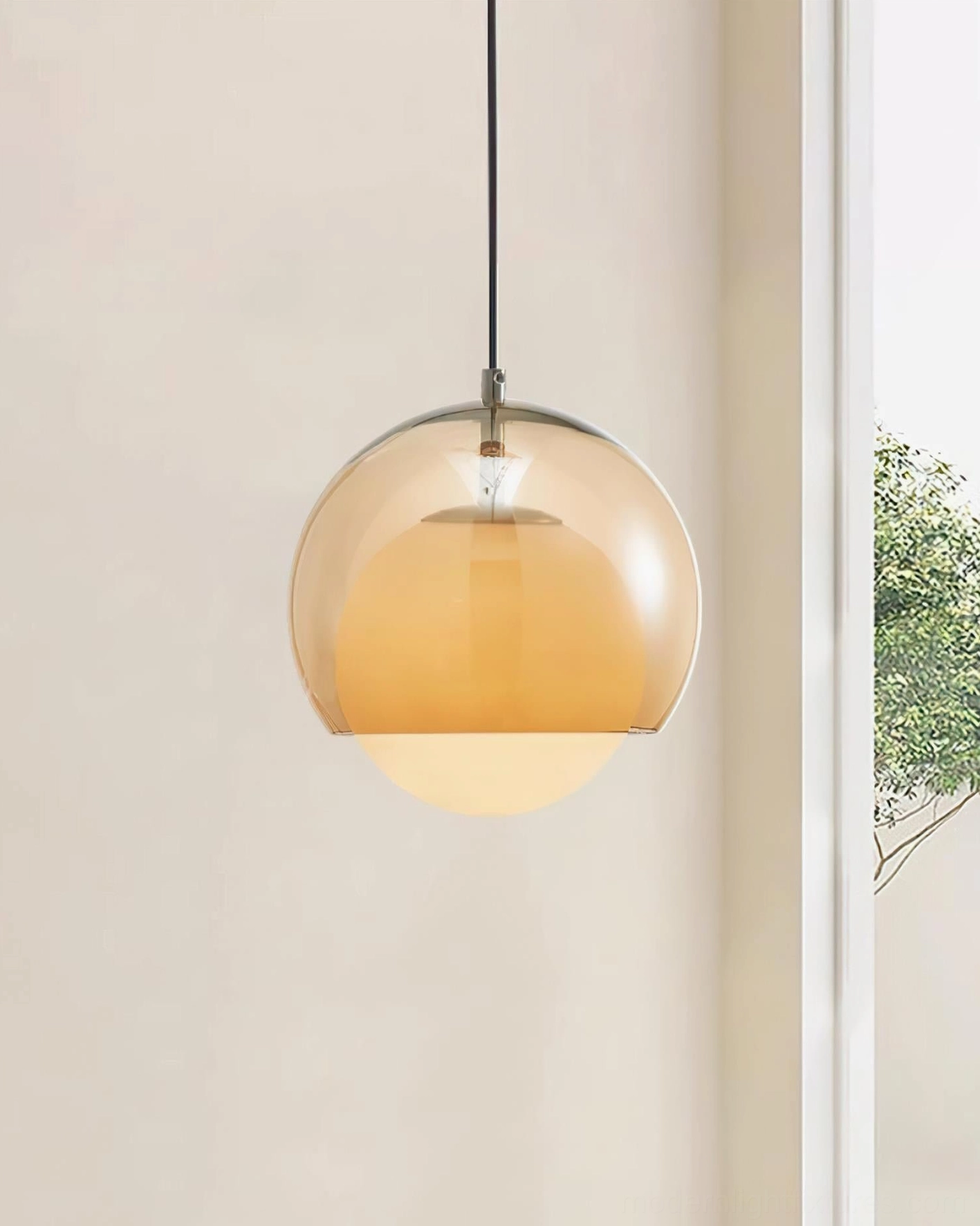 Spherical pendant light by window showing warm glass diffusion with natural light and green outdoor scenery