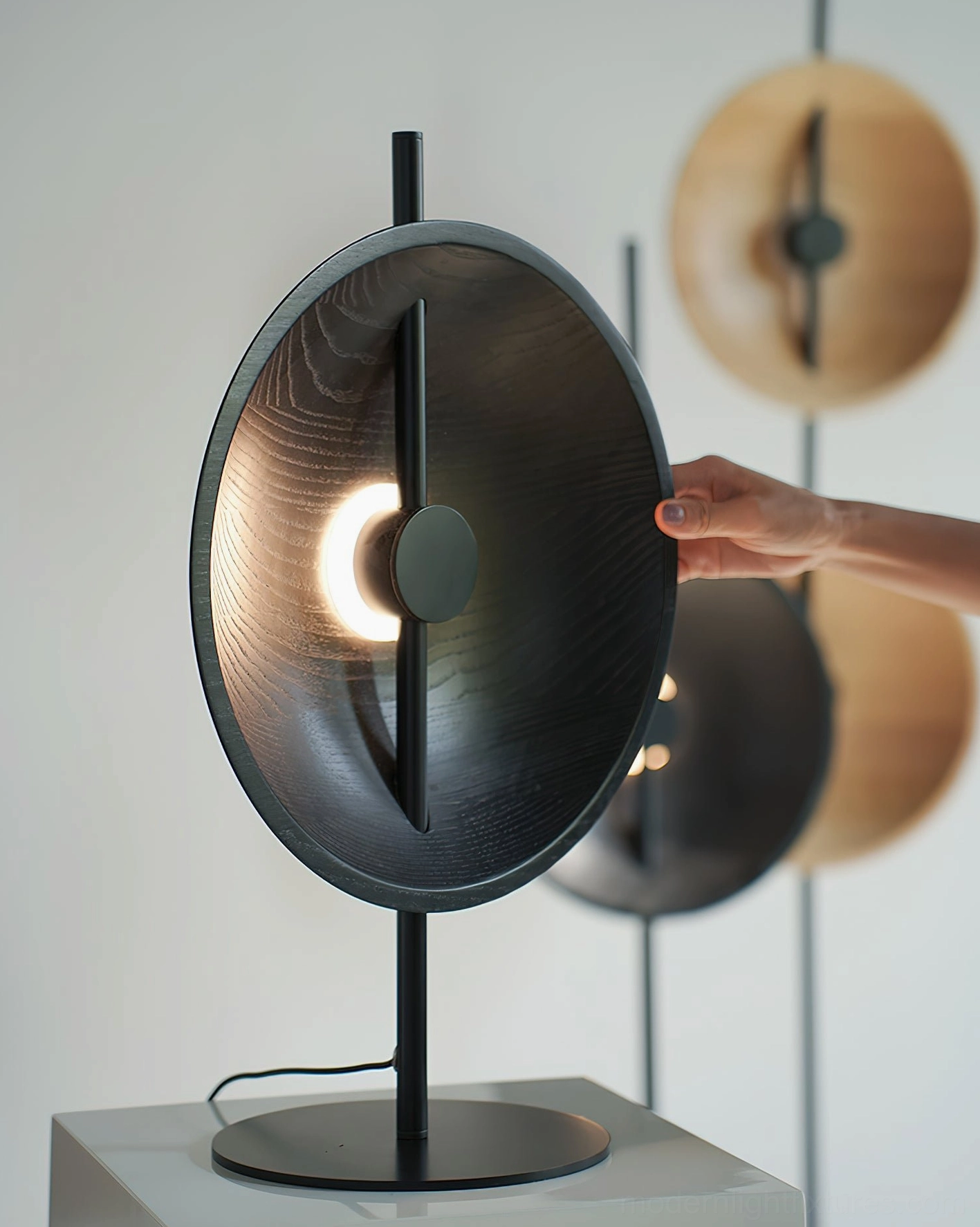 Illuminated Mito circular table lamp showing warm light diffusion from central aperture and architectural design
