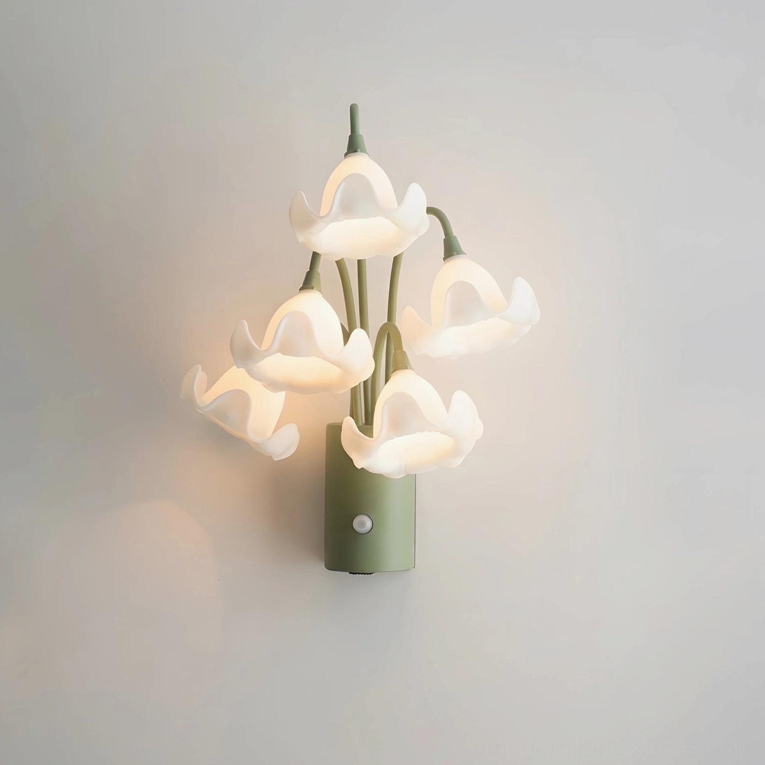 Mivella white acrylic flower wall sconce with illuminated soft ruffled blooms and sage green base on plain wall background