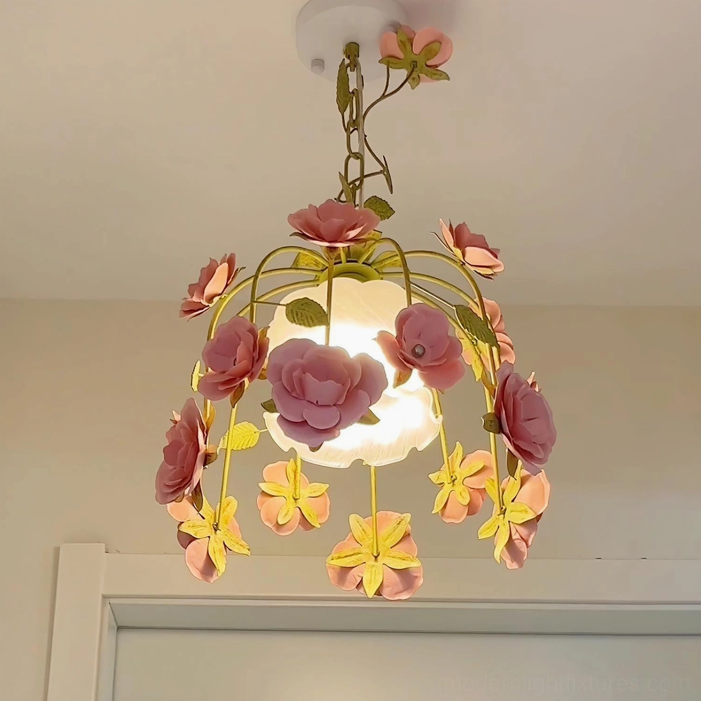 Mixed floral pendant chandelier with yellow and two-tone pink hand-carved blooms, white frosted glass shade, indoor entryway setting
