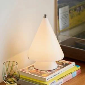 Miza white LED table lamp illuminated on stacked books and wooden desk with warm ambient lighting