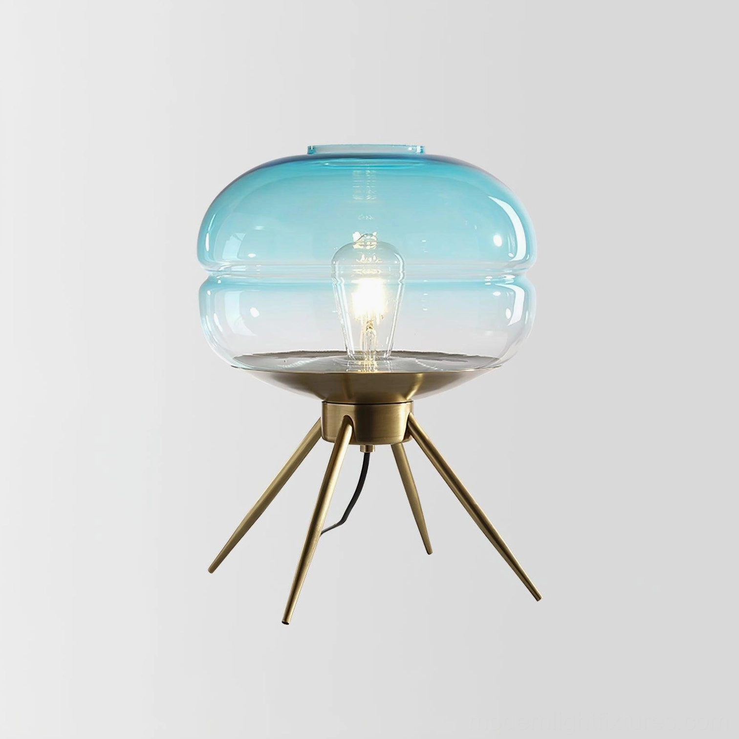 Gradient blue tiered glass table lamp with brass base in front view on studio white background