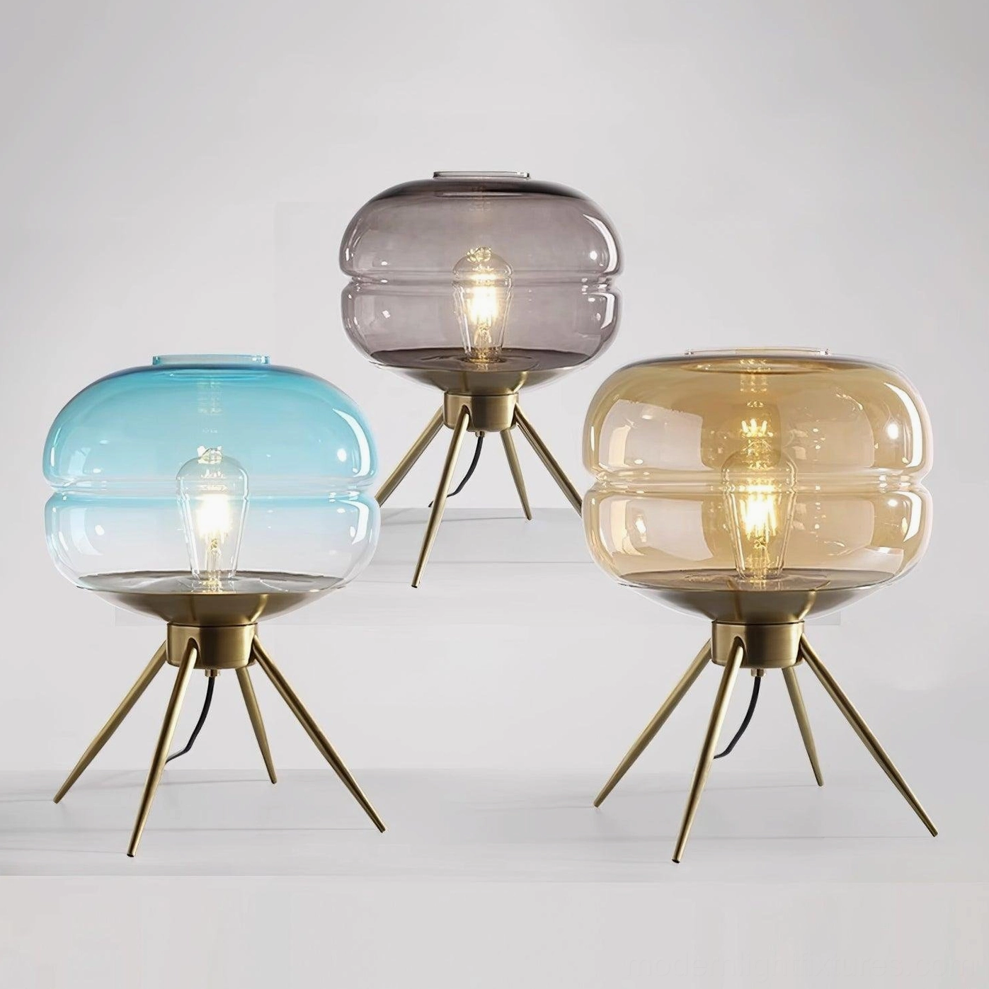 Moda table lamp color variations set showing amber, smoke gray, and gradient blue glass shades with matching brass bases