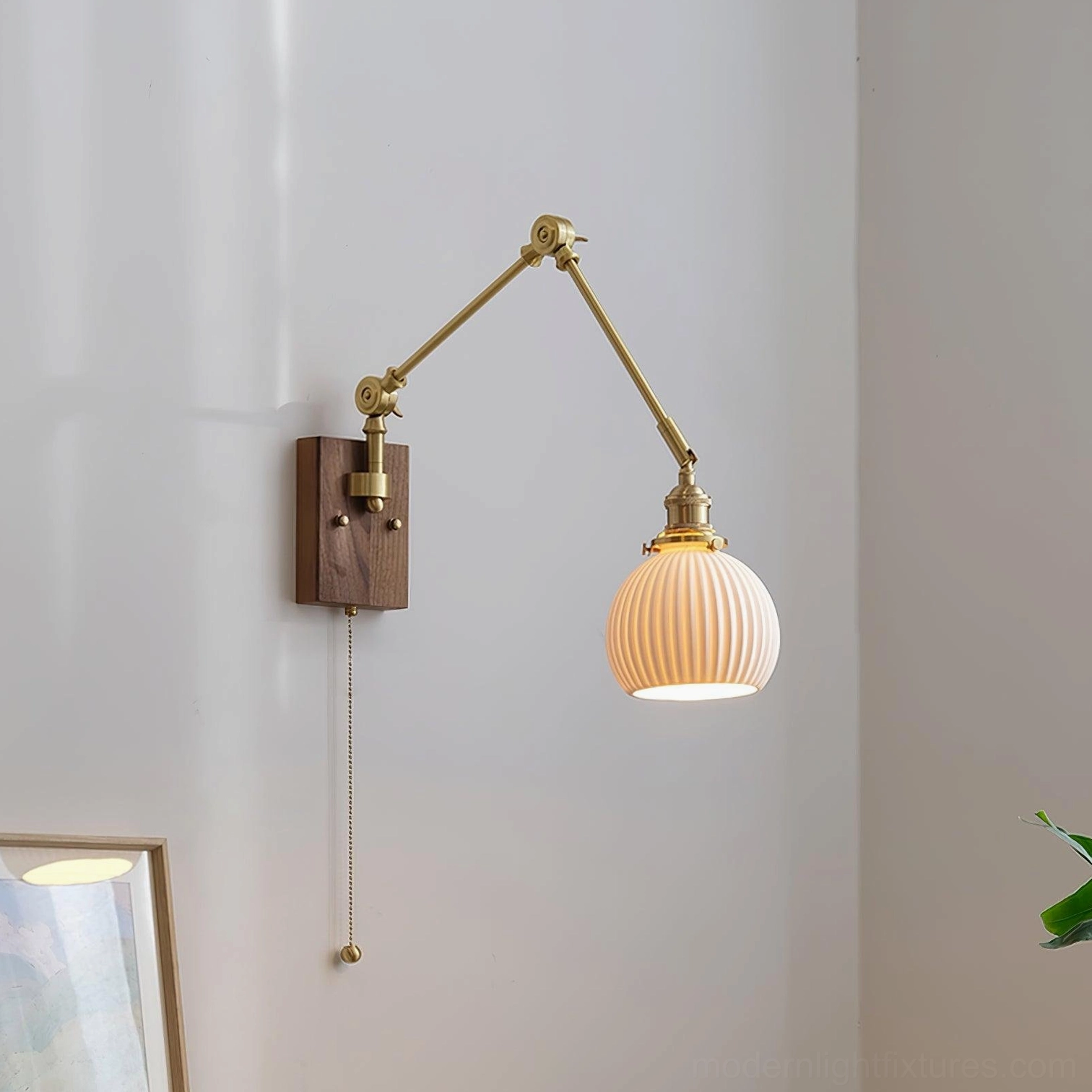 Model A compact swing arm wall sconce with white ceramic globe, mounted beside bedroom furniture