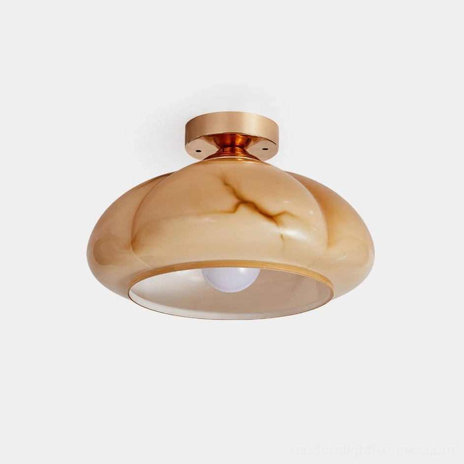 Modern amber glass semi-flush ceiling light with polished brass base, close-up product view on white background